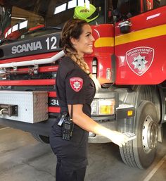 a woman in uniform standing next to a fire truck