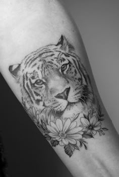 a black and white photo of a tiger with flowers on it's arm,