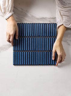 a person holding onto a blue mat on a white surface with their hands resting on it