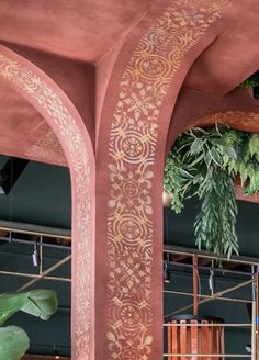 an ornately painted archway in a building with plants hanging from it's sides