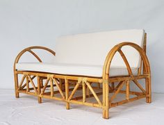 a couch made out of bamboo with white cushions on it's back and sides