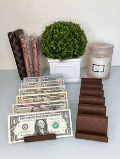 a stack of money sitting next to some candles and a potted plant on top of a table