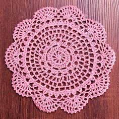 a crocheted doily on a wooden surface with the center piece cut out