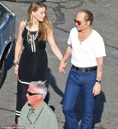 a man and woman holding hands while standing next to a car