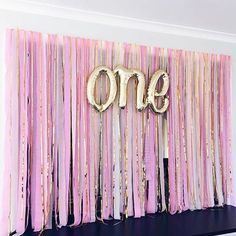 a pink and gold birthday backdrop with the word one on it