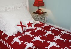 a red and white bed topped with pillows next to a night stand on top of a table