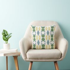 a chair with a pillow on it next to a small table and potted plant