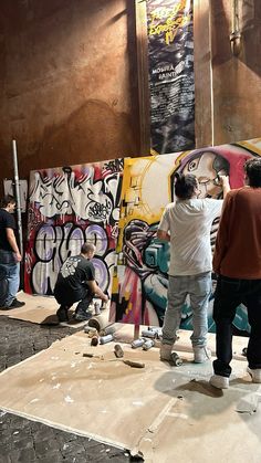 three men are painting graffiti on the wall