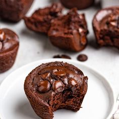 a chocolate muffin on a plate with one bite taken out