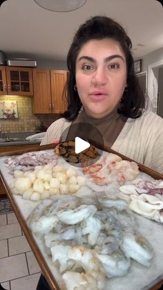 a woman holding up a tray full of food