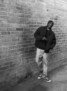 a man standing in front of a brick wall