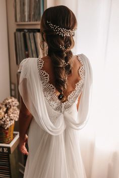 the back of a woman's wedding dress with sheer sleeves and beaded details