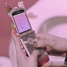 a person holding a cell phone in their hand with candy on the screen and an mp3 player attached to it