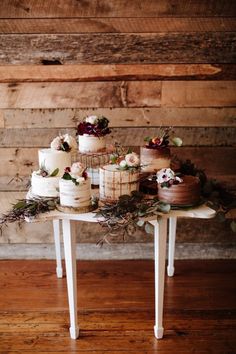 a table topped with lots of cakes covered in frosting on top of a wooden floor