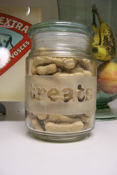 a glass jar filled with dog treats sitting on top of a counter next to fruit