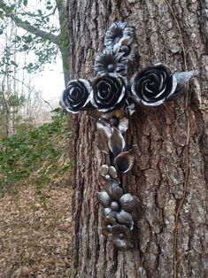 a cross made out of metal sitting on the side of a tree