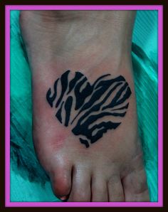 a heart shaped zebra print tattoo on the bottom of a person's foot,