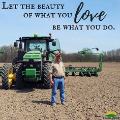 a man standing in the middle of a field next to a tractor