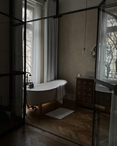 a bath tub sitting next to a window in a room with wooden floors and walls