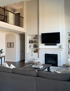 a living room with couches and a tv mounted on the wall above it's fireplace