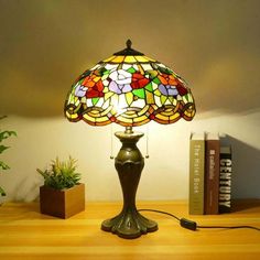 a lamp that is sitting on top of a table next to some books and a plant