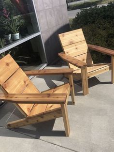 two wooden chairs sitting next to each other on the cement ground near plants and bushes