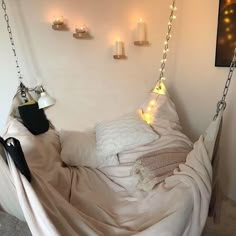 a bed with a white blanket hanging from it's side and some candles on the wall