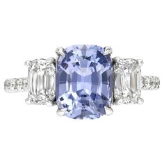 an oval blue and white diamond ring with three baguets on the side, set in