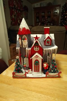 a red and white christmas house sitting on top of a wooden table