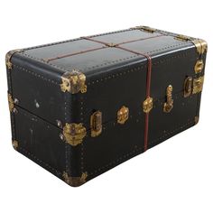 an old black trunk with gold trim and rivets on the sides is shown