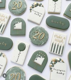 many decorated cookies are displayed on a white tablecloth with green and gold lettering that says 20th birthday