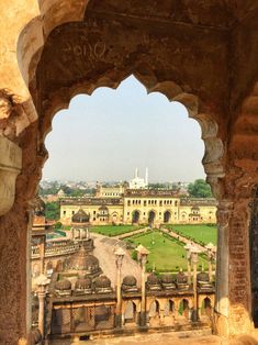 the view from inside an old building looking down on a large garden and buildings in the distance