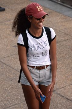 a woman walking down the street in shorts and a baseball cap