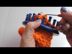 a woman is holding an orange and blue object with crochet on the end