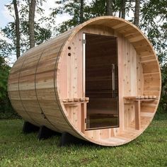 a wooden barrel sauna in the grass