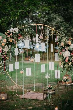 an outdoor wedding ceremony with flowers and cards on the arch, surrounded by greenery