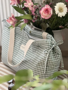 pink and white flowers are in a plaid bag