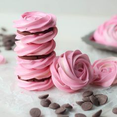 pink frosted cookies stacked on top of each other with chocolate chips scattered around them