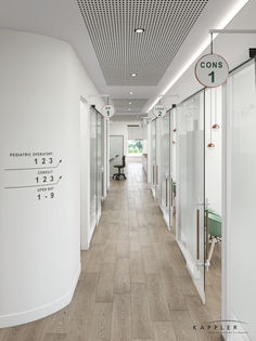 an office hallway with white walls and wood flooring, along with glass partitions