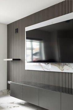 a flat screen tv mounted to the side of a wall in a living room with black and white striped walls