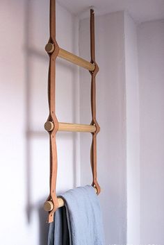 a wooden ladder hanging from the side of a wall next to a blue towel rack