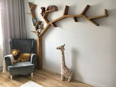 a baby's room with a chair, stuffed animals and a tree shelf on the wall