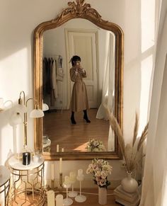 a woman taking a selfie in front of a mirror with candles and vases