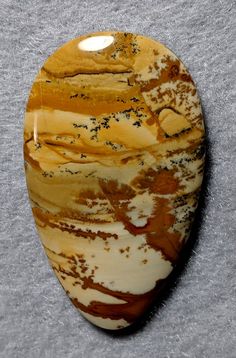 a brown and white marble with black speckles on it's side, sitting on a gray surface