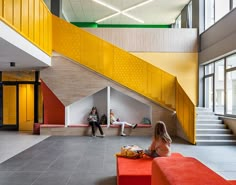 a woman sitting on a red bench in front of a yellow and white stair case