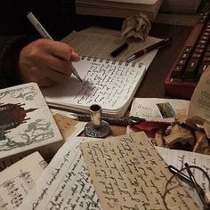 a person sitting at a desk writing on some old books with pen and eyeglasses