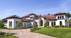 a large white house sitting on top of a lush green field next to a palm tree