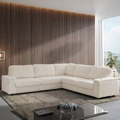 a living room with a large white sectional couch and coffee table in front of a wooden paneled wall