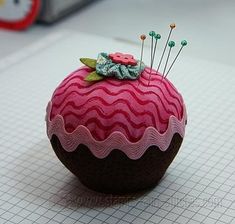 a pink and brown cupcake with buttons on it sitting on a piece of graph paper