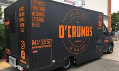 a black truck with orange lettering is parked in front of a building on the street